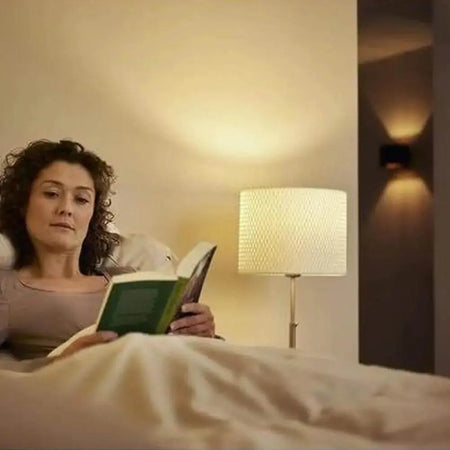 Philips CorePro LEDcapsule G4 2W bulb, warm white (827), bedside lamp scene with a woman reading in bed. UAE