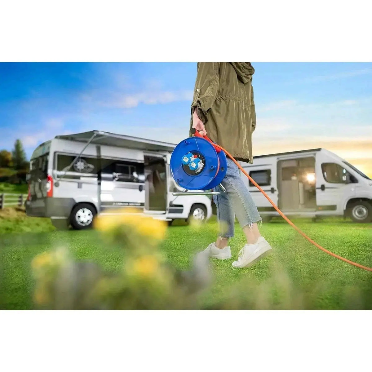 Brennenstuhl Garant 2-socket cable reel, blue IP44, 25m, carried by a person outdoors near camper vans. UAE