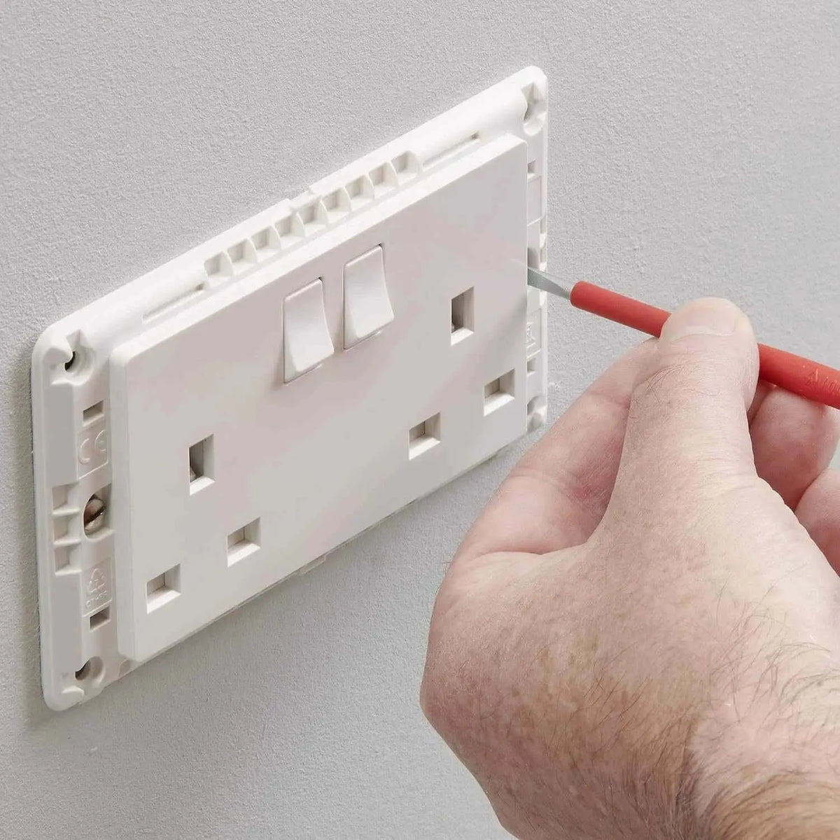 MK Essentials 13A 1G SP switched socket, white MV2757WHI; wall outlet with hand holding screwdriver. UAE