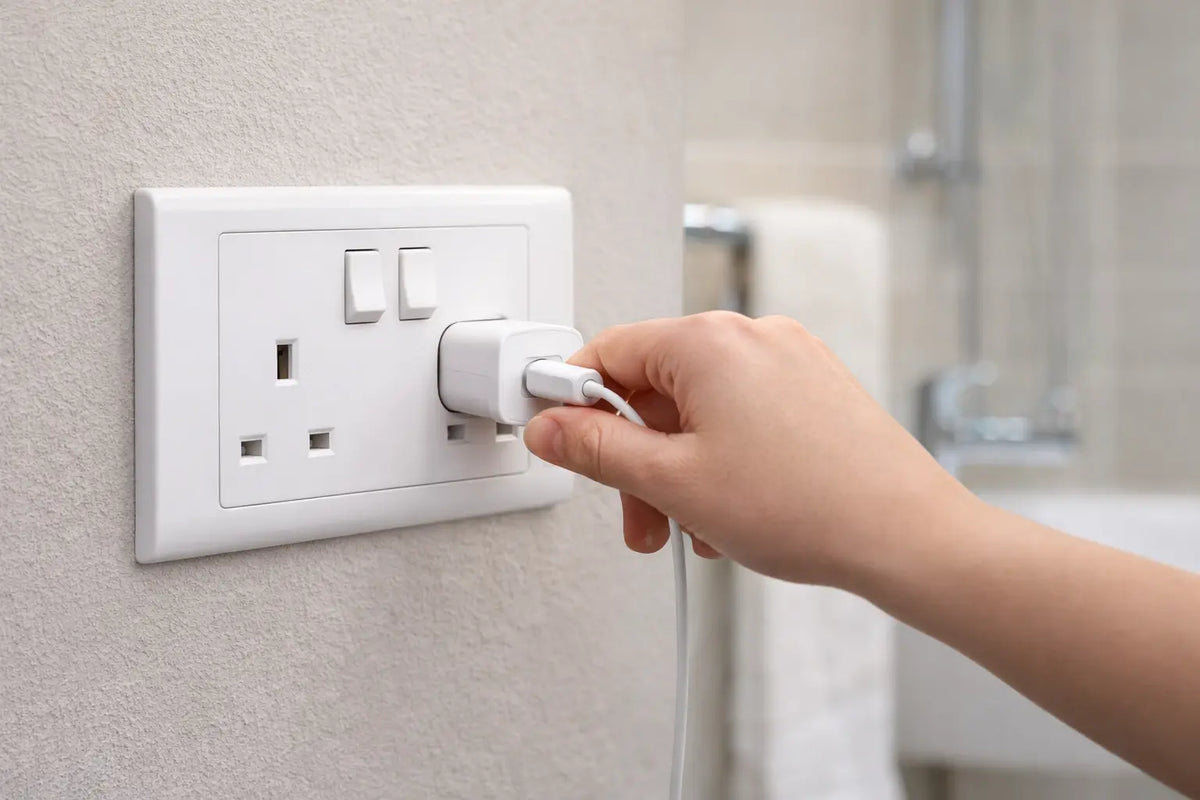 MK Electric MV2747WHI 13A switched socket, white wall outlet; hand inserts plug (front view) UAE