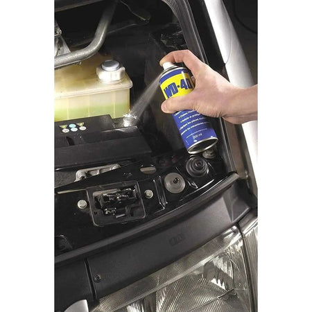 WD-40 Multi-Use Product Original Rust Remover, 330ml, hand spraying near car engine bay. UAE