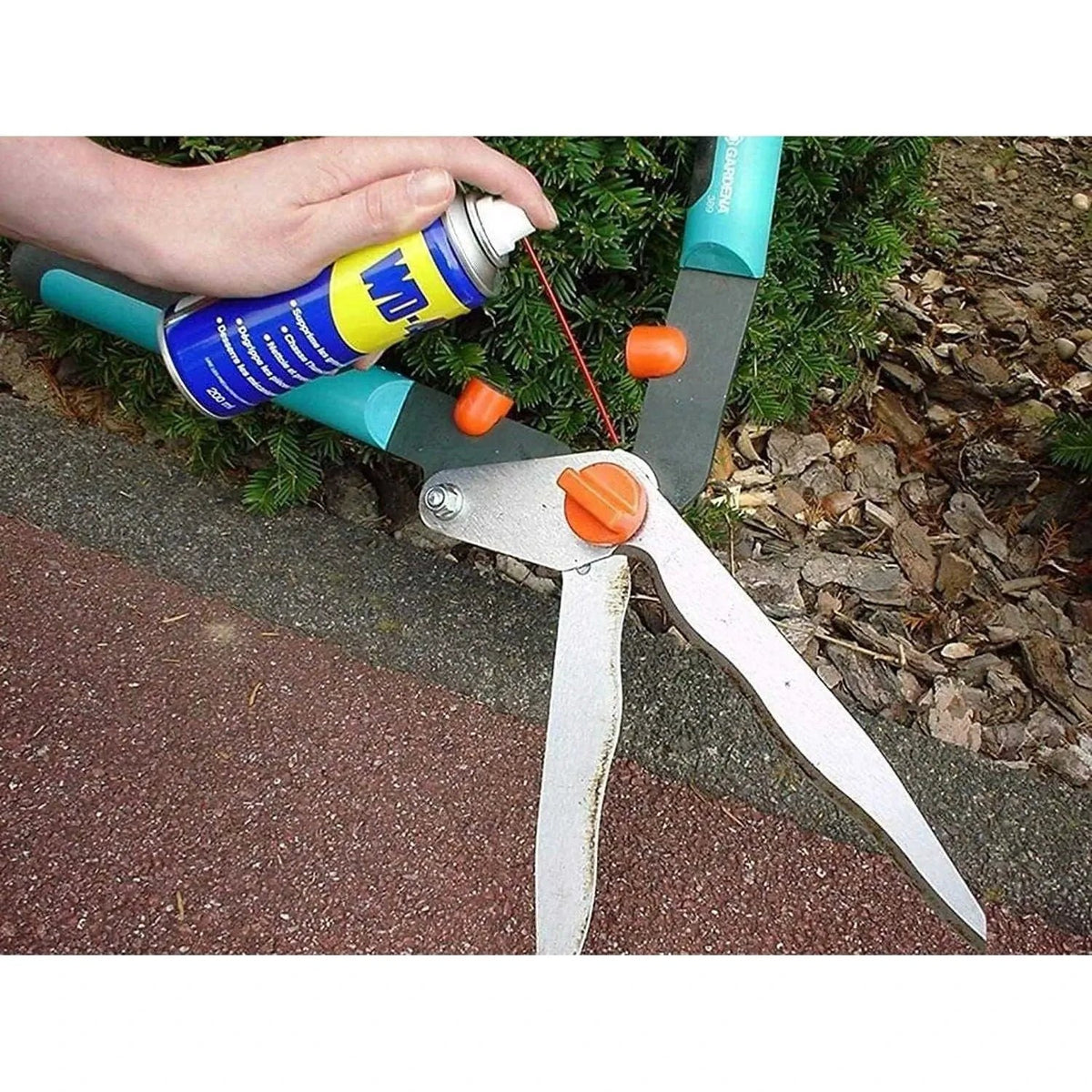 WD-40 Multi-Use Product Original Rust Remover, 330ML being sprayed on a rusted metal tool with orange knobs UAE