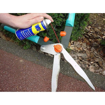 WD-40 Multi-Use Product Original Rust Remover, 330ML being sprayed on a rusted metal tool with orange knobs UAE