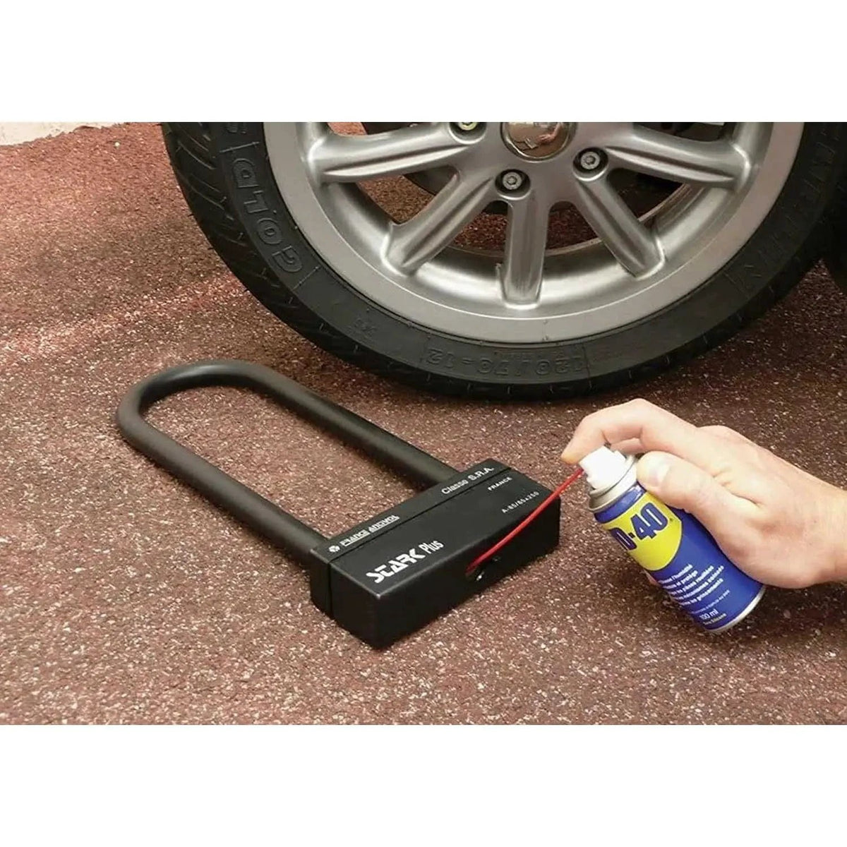 WD-40 Original Rust Remover 330ml spray can beside a black rust-remover device with curved handle near a car wheel. UAE