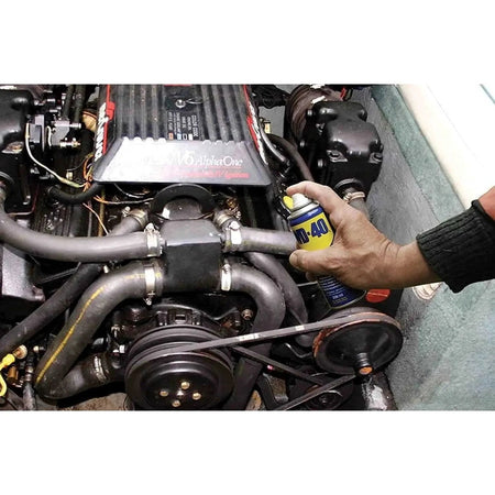 WD-40 Multi-Use Product Original Rust Remover 330ml spray can held in hand beside a car engine bay. UAE